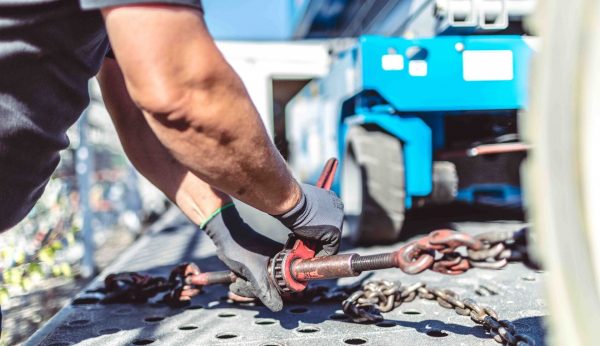 Arbeiter befestigt eine Hebebühne auf dem LKW für den sicheren Transport.