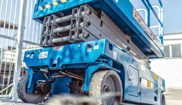 Nahaufnahme einer blauen Weiland-Scherenarbeitsbühne mit Fokus auf das Fahrwerk und die Hubmechanik.